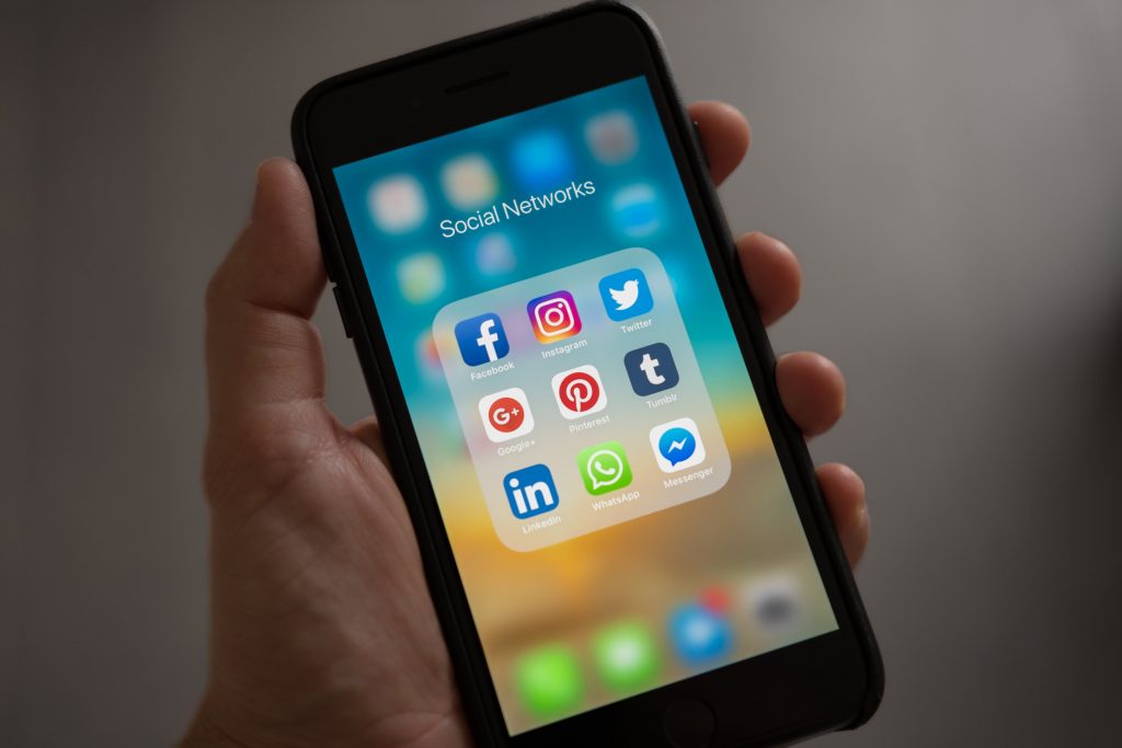 Image of a hand holding a smartphone with icons for social media apps